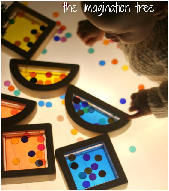 DIY light box with a baby on top and colorful buttons of all colors, and a moon and square that are yellow, orange, and blue.